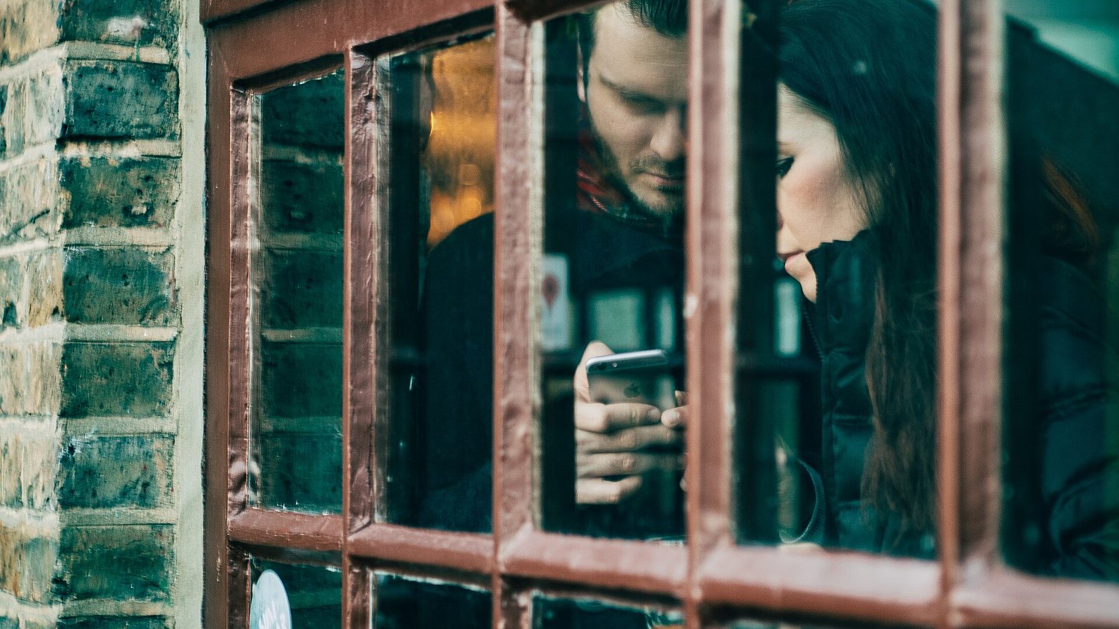 Pencere önünde telefonla konuşan bir kişi, dışarıda gün ışığı